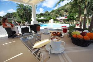 un tavolo con una tazza di caffè e frutta accanto alla piscina di Residence Hotel La Giara a Città di Lipari