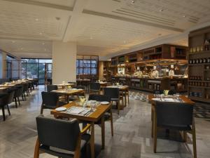 a restaurant with wooden tables and chairs and a bar at Novotel Chennai Chamiers Road in Chennai