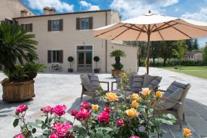 a patio with chairs and an umbrella and flowers at Pistoia Nursery Campus - agriturismo in citt&agrave; in Pistoia