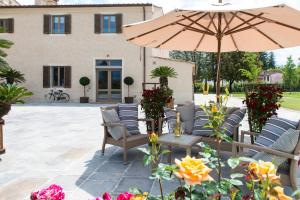 a patio with chairs and an umbrella and flowers at Pistoia Nursery Campus - agriturismo in citt&agrave; in Pistoia