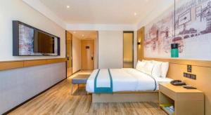 une chambre d'hôtel avec un lit et une télévision à écran plat dans l'établissement City Comfort Inn Zhanjiang International Trade Dingsheng Plaza, à Zhanjiang