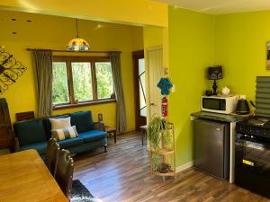 a living room with yellow walls and a kitchen at Quaint Country Cottage 