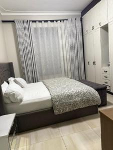 a bedroom with a bed and a window with curtains at Ahwera beautiful homes in Kampala