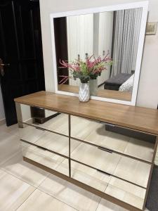 a dressing table with a mirror and a vase with flowers at Ahwera beautiful homes in Kampala +1 photo