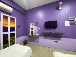 a purple room with a bed and a tv on a wall at Hotel station 24 in Sungai Besar