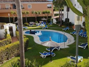 an outdoor swimming pool with chairs and an umbrella at Luxe Villa Puerto Banus in Marbella