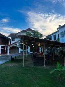 a group of people sitting at a picnic table under a tent at Social Garden Hostel in Chiang Rai