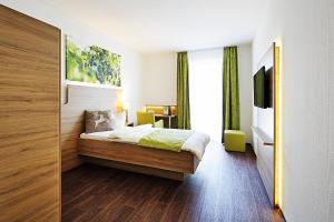 a hotel room with a bed and a television at Green Deer Bavarian Hotel in Langenbruck