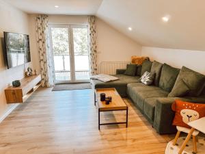 a living room with a green couch and a table at Bachgeflüster-Suite in Bad Koetzting