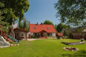 ein Haus mit einem orangenen Dach und einem grünen Hof in der Unterkunft Nad Rumianem in Rybno