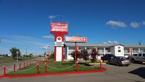 un panneau indiquant une station-service devant un bâtiment dans l'établissement Canadian Motor Inn, à Grande Prairie