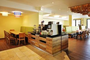 a restaurant with a counter with a coffee maker at Green Deer Bavarian Hotel in Langenbruck