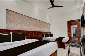 ナーグプルにあるHotel Vijayshree Innのベッド2台と椅子があるホテルの部屋