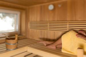 una persona sentada en una sauna con sus pies sobresaliendo en Haus Bergkristall, en Sankt Anton am Arlberg