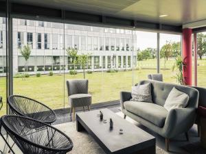a living room with chairs and a couch and a table at Hôtel Mercure Nantes Ouest Saint-Herblain Zenith in Saint-Herblain