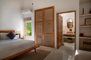 a bedroom with a bed and a mirror and a door at SĀMA Ahangama in Ahangama