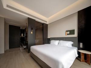 a bedroom with a large white bed and a table at Lezhizhi Anyu Hotel, Zhuge Liang Plaza, Wanda Branch in Xiangyang