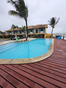 a large swimming pool with palm trees and a building at Beachfront House with Pool and Gourmet Area in Rio das Ostras