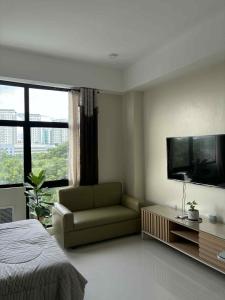 1 dormitorio con sofá y TV de pantalla plana en Mactan Plains Residences Studio Unit, en Punta Engaño