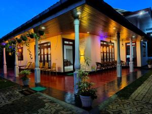 een gebouw met zuilen, tafels en stoelen in de regen bij Freedom-Inn Resort Villa in Tangalle
