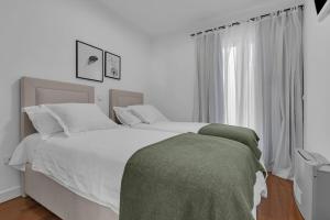 a white bedroom with two beds and a window at Villa Svilla - Makarska Exklusiv in Drasnice