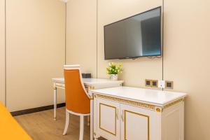 広州市にある广州维福顿白宫酒店の机と壁にテレビが掛かっている部屋