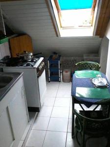a kitchen with a stove and a table and a window at Magdi apartman in Pusztavacs