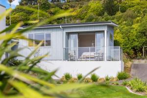 a small house with a balcony with two chairs at Aston Road Villa Bed & Breakfast in Waikanae