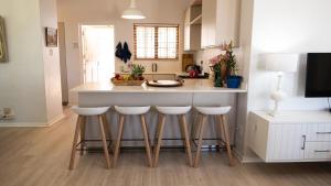 a kitchen with a island with bar stools at Mountainside Family Beach House - Pet Friendly in Hermanus