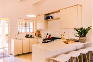 a kitchen with white cabinets and bar stools at Mountainside Family Beach House - Pet Friendly in Hermanus