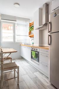 a white kitchen with a table and a refrigerator at Santander Centro in Santander