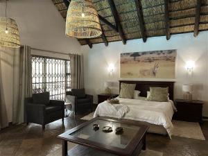 a bedroom with a bed and a table and a chair at Halali Wilderness Private Game Ranch in Hammanskraal +45 photos