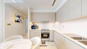 a kitchen with white cabinets and a stove top oven at Stay Steps from Burj Khalifa & Dubai Mall With Skyline Views 2BR Downtown Like Home in Dubai