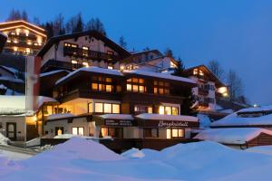 un edificio con nieve delante de él por la noche en Haus Bergkristall, en Sankt Anton am Arlberg