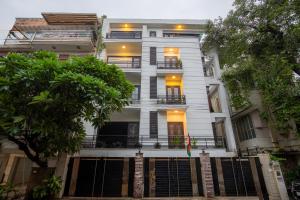a white building with a tree in front of it at BedChambers Serviced Apartments South Extension in New Delhi