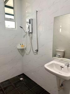 a white bathroom with a shower and a sink at MU Homestay in Simpang Ampat