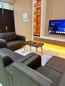 a living room with couches and a table and a tv at MU Homestay in Simpang Ampat