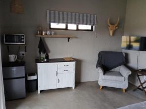 a small room with a chair and a white cabinet at Aloe Thorn Self Catering in White River