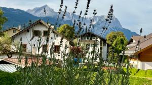 a house with mountains in the background with flowers at Studio Bergblick 5 in Garmisch-Partenkirchen