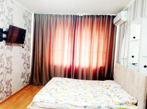 a bedroom with a bed in front of a window at Квартира in Aktobe