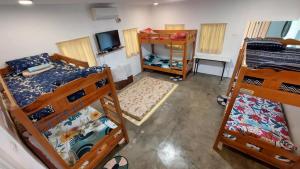 a room with three bunk beds and a television at Beach House, San Juan, La Union in San Juan