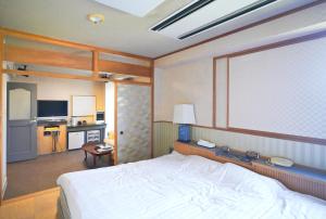 a bedroom with a large white bed and a kitchen at ホテル韮崎インター in Nirasaki
