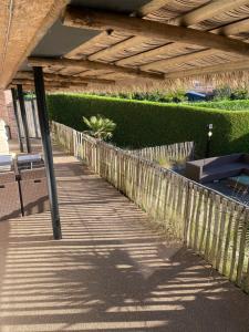 a wooden walkway under a roof with a fence at Vakantiewoning Oase in Groede