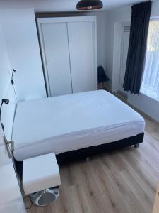 a white bed in a room with wooden floors at Vakantiewoning Oase in Groede