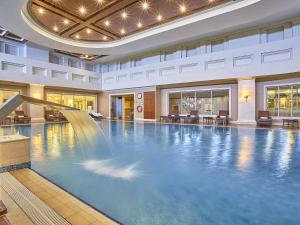 a swimming pool in a hotel with a fountain at Rixos President Hotel Astana in Astana