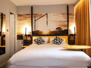 a bedroom with a large white bed with pillows at Ibis Styles Clermont-Ferrand République in Clermont-Ferrand