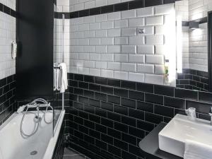 a black and white bathroom with a tub and a sink at Ibis Styles Clermont-Ferrand République in Clermont-Ferrand +105 photos