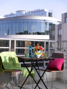 einen Tisch und Stühle mit einer Schüssel Blumen auf dem Balkon in der Unterkunft Thon Hotel Residence Parnasse Aparthotel in Brüssel