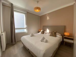 a bedroom with a large white bed with a window at Beauregard- Charmant 2 chambres, terrasse & garage in Annecy