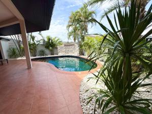 a swimming pool in a yard with palm trees at 2 bedroom pool villa, near Pattaya city centre in Pattaya South